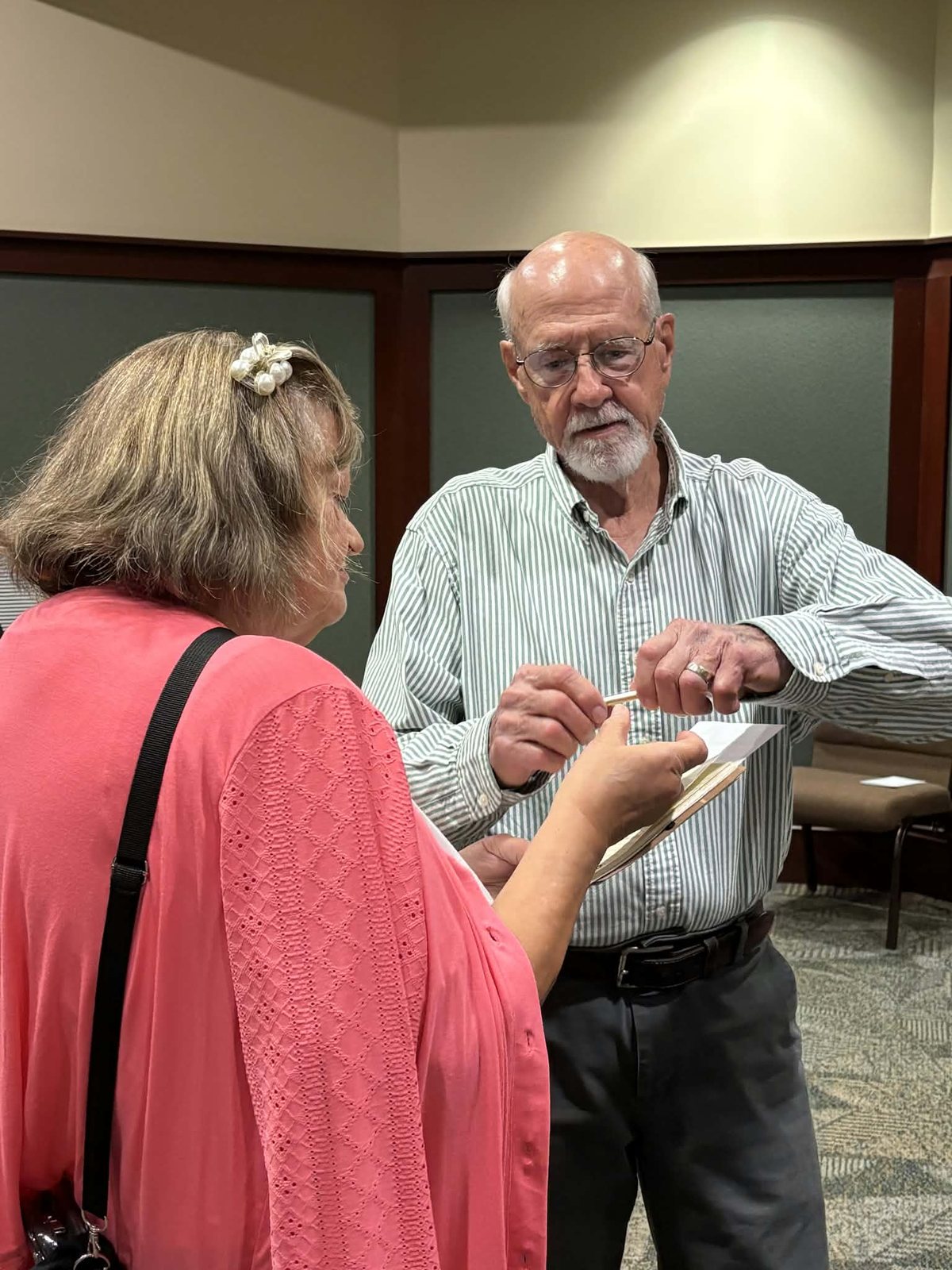 A resident writes his name and address on a notepad held by another attendee.